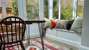 A cozy seating area with a bench, a wooden chair, and a patterned rug.