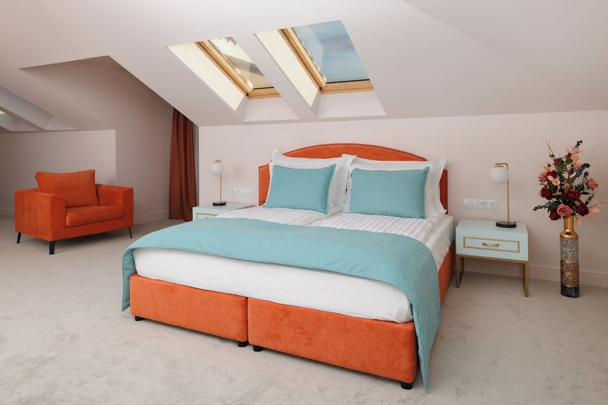 Une chambre à coucher avec un grand lit, une table de chevet, une chaise et un vase rempli de fleurs.
