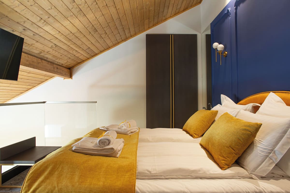 Une chambre d’hôtel avec un lit, un plafond en bois, une armoire et une table de chevet.