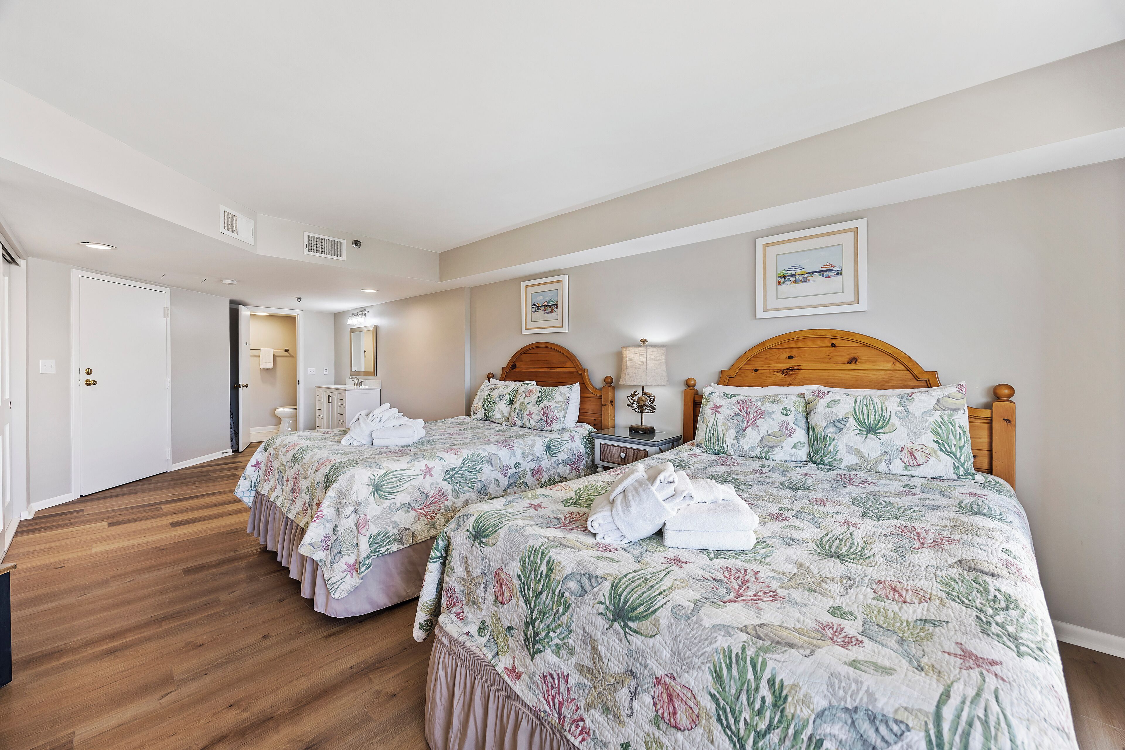 A hotel room with two beds, wooden headboards, and a large window.