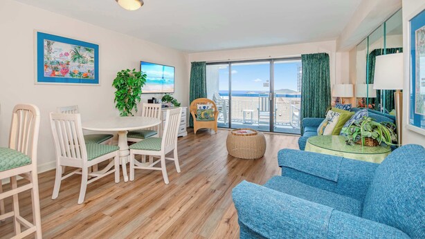 A living room with a dining table, chairs, a sofa, a TV, a plant, and a balcony with a view. - Peaceful Cabana Section*Indoor/Outdoor Pools*Mc61 (Myrtle Beach)