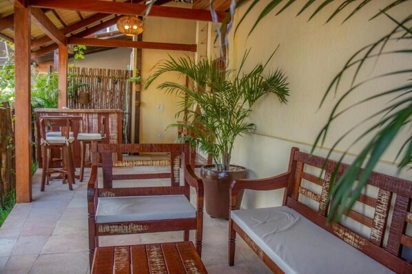 A covered outdoor seating area with wooden furniture and a potted plant. - Pousada SunBrazil (Jijoca de Jericoacoara)