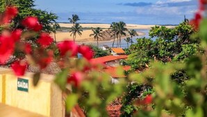 Vista costera con playa, palmeras y un edificio de techo rojo.