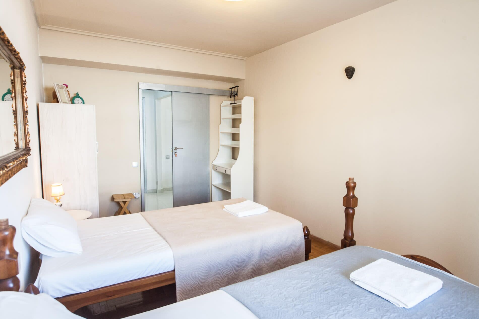 A bedroom with two beds, a wardrobe, and a mirror.