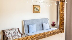 A room with a large ornate mirror, a patterned sofa, a floral armchair, and a small table with a vase. - Gorgeous 2 bedrooms apt at Exarcheia (Athens)
