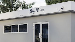 A building with a sign reading "Stay Fit ROOM" and a security camera mounted on the wall. - Beautiful detached home with pool and gym! (Willemstad)