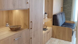 A modern living room with wooden cabinetry, a sofa, and a stone wall. - Studio-cabin apartment (Combloux)