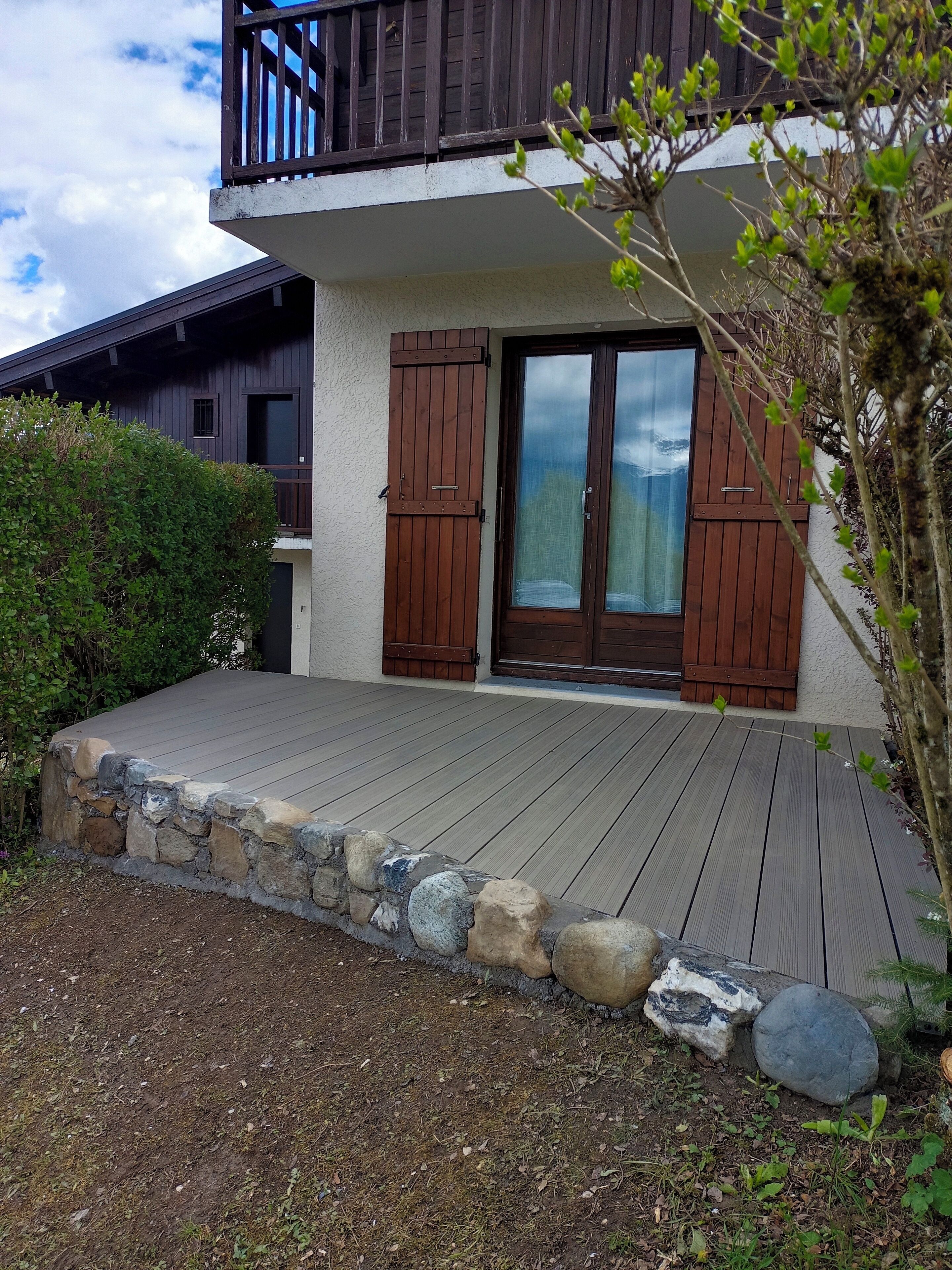 Ein zweistöckiges Gebäude mit einer Holzterrasse und einer Steingrenze.