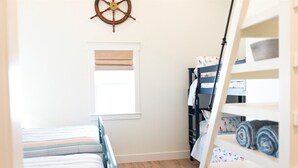 Ein Schlafzimmer mit einem Bett, einem Fenster, einem Kleiderschrank und einem an der Wand befestigten Schiffsschwungrad.