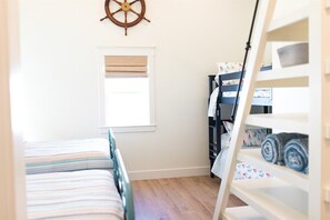 A bedroom with a bed, a window, a wardrobe, and a wall-mounted ship's wheel. - Brown Eyed Girl at River Rocks Plantation (Guntersville)