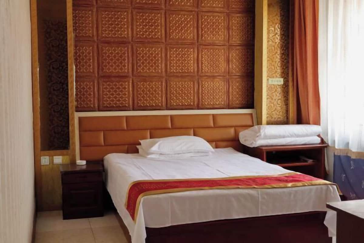 Una habitación de hotel con una cama grande, un cabecero de madera, una mesita de noche y otra mesilla.