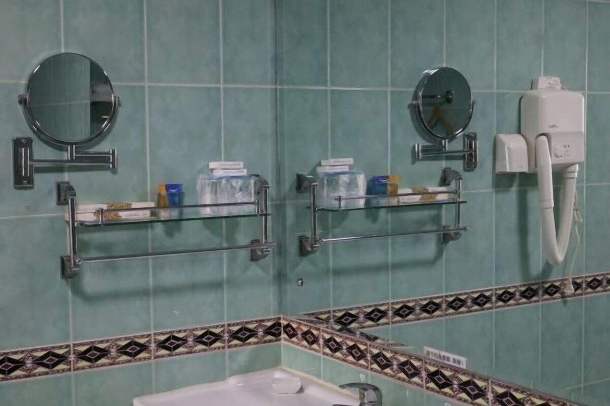 Un baño con dos lavamanos, espejos y un inodoro.