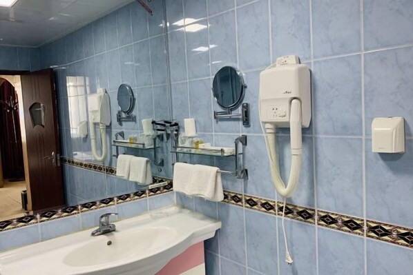 Un baño con lavamanos, espejos y un perchero para toallas.