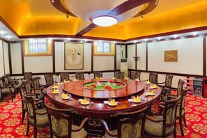 Un salón de conferencias con una mesa redonda, sillas y piso cubierto de alfombra roja.