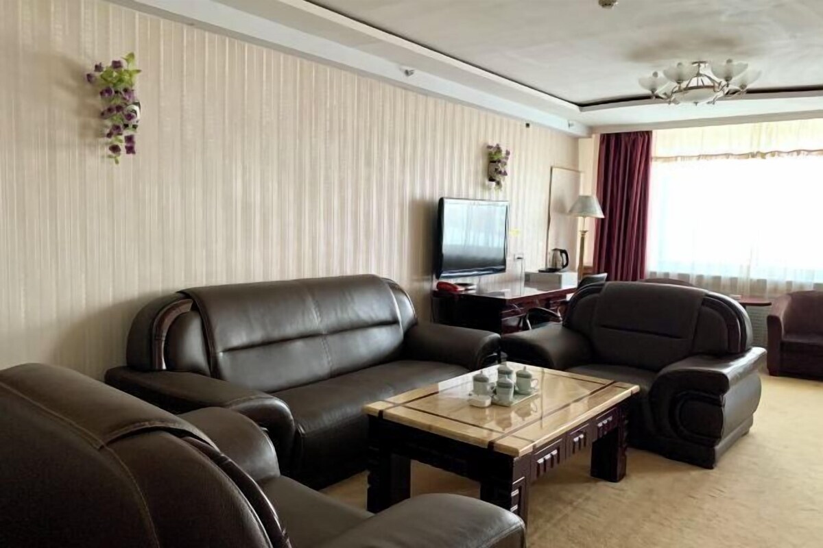 Una sala de estar moderna con sofás de cuero, una mesa de centro de vidrio, un televisor de pantalla plana y plantas decorativas.
