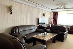 Uma sala de estar moderna com sofás de couro, uma mesa de centro de vidro, uma televisão de tela plana e plantas decorativas.