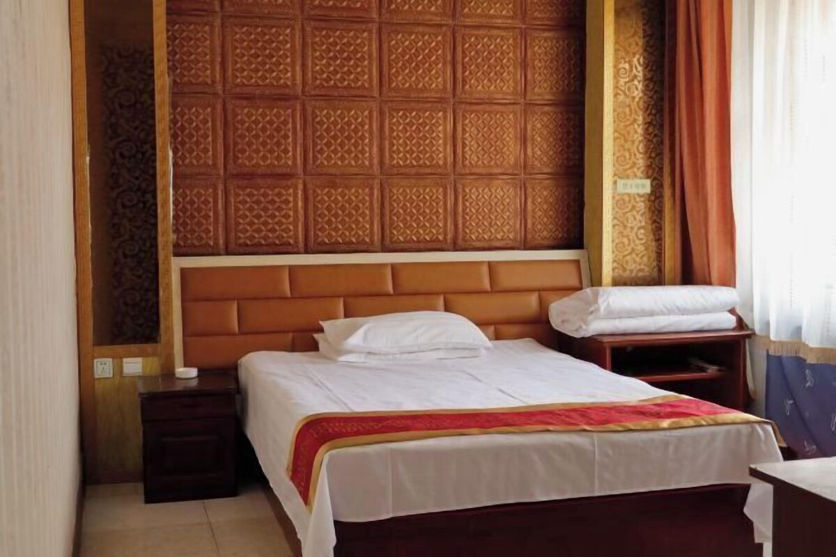 Una habitación de hotel con cabecera de madera, cama con ropa de cama blanca, mesita de noche y una pequeña mesa.