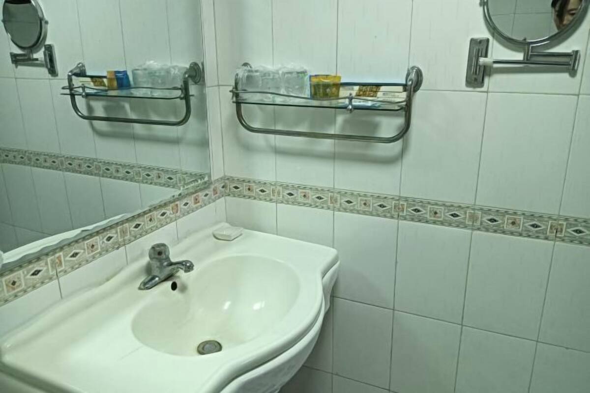 A bathroom with a white sink, two glass shelves above the sink, and a mirror on the wall.