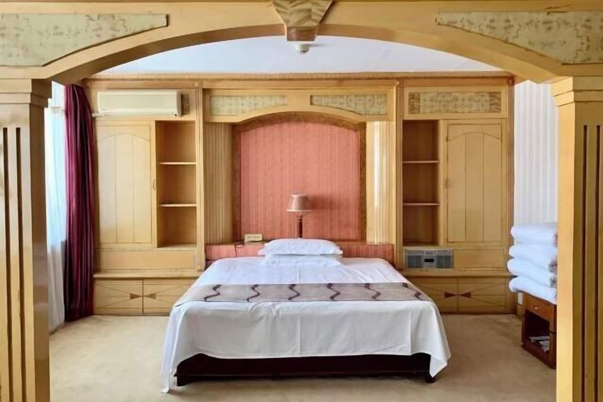 Habitación de hotel con una cama grande, una lámpara de noche y estantes empotrados.