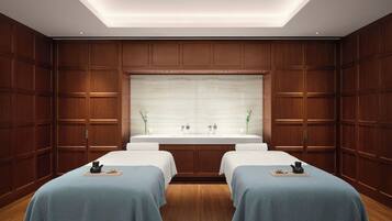A hotel room with a wooden panel wall, a large mirror, and two beds with blue bedspreads.