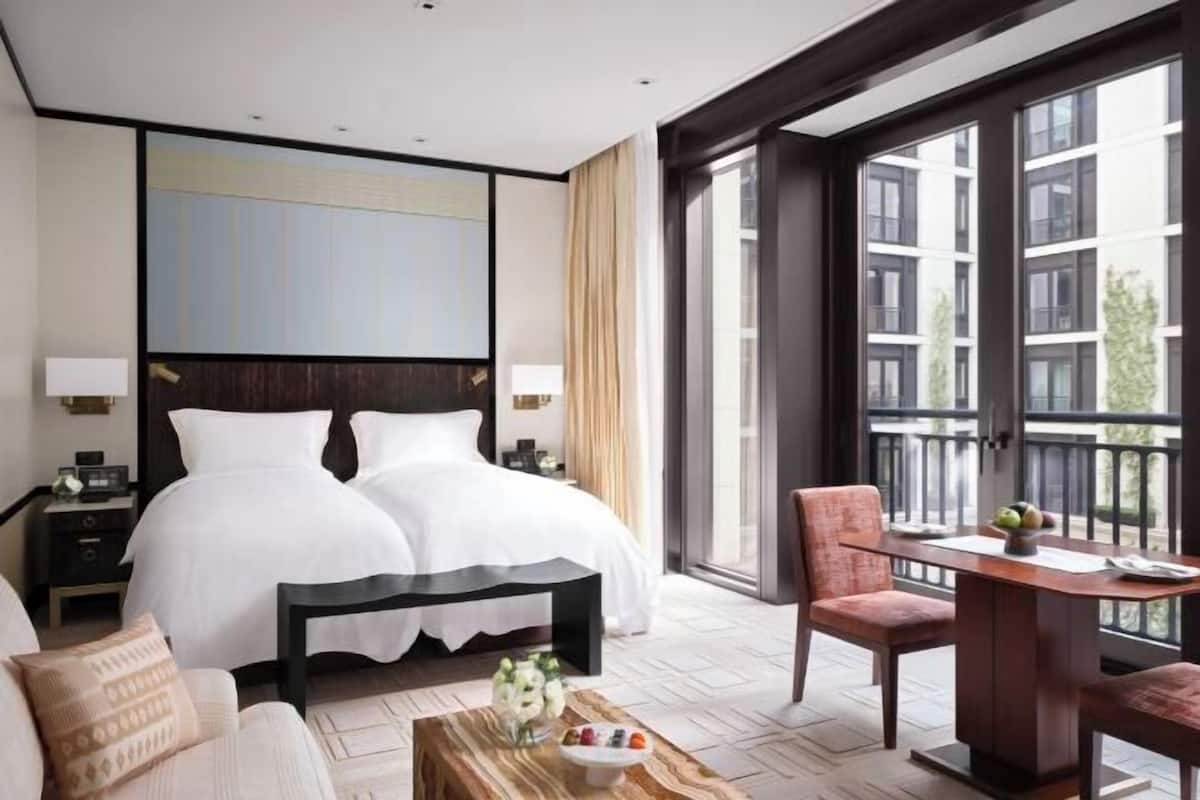 A hotel room with a large bed, a desk, a chair, and a view of the outside.
