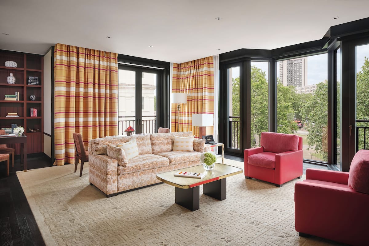 A modern living room with a patterned sofa, a red armchair, and a coffee table.