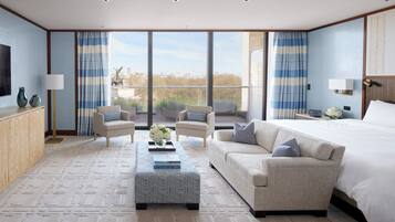 A spacious bedroom with a large bed, two armchairs, a sofa, and a coffee table.