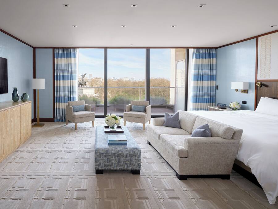 A spacious bedroom with a large bed, two armchairs, a sofa, and a coffee table.