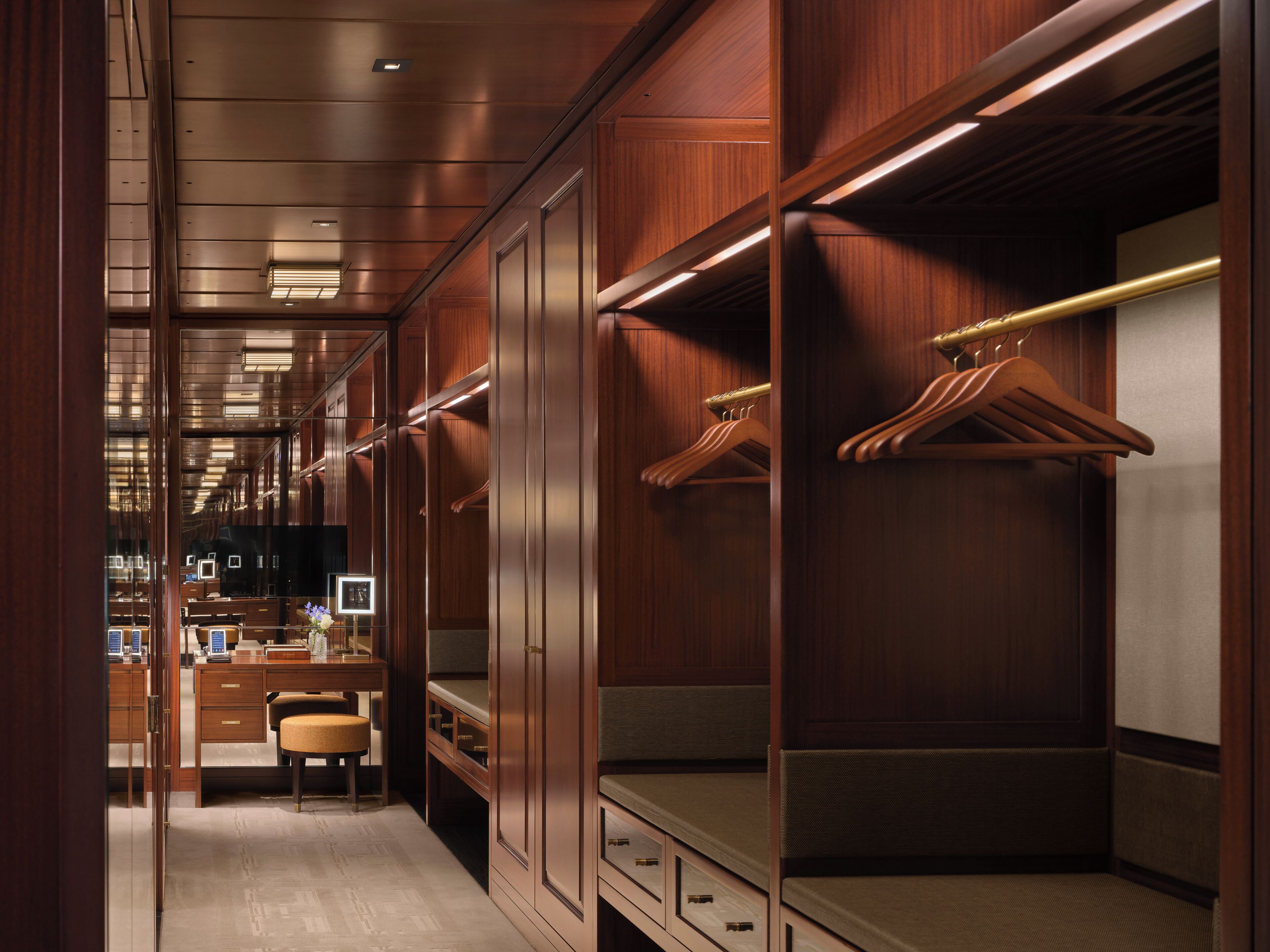 A walk-in closet with wooden doors, a desk, and a chair.