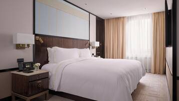 A modern hotel room with a large bed, bedside tables, a nightstand, and a large mirror.