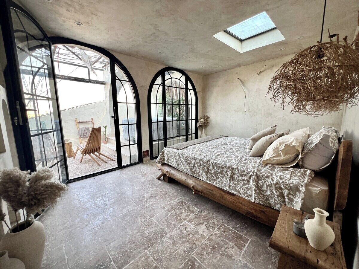 Ein Schlafzimmer mit einem Bett, einem Oberlicht, einem großen Fenster und Blick ins Freie.