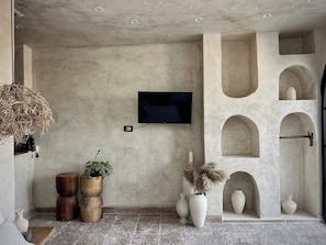 A room with a TV mounted on the wall, a potted plant, and decorative vases.