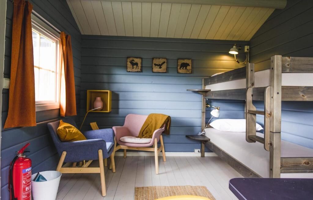 A cozy cabin interior with a bunk bed, a small desk, a chair, and a window with curtains.