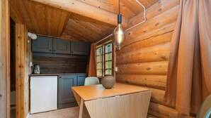 A compact kitchen with wooden walls, a small refrigerator, and a table with a vase.