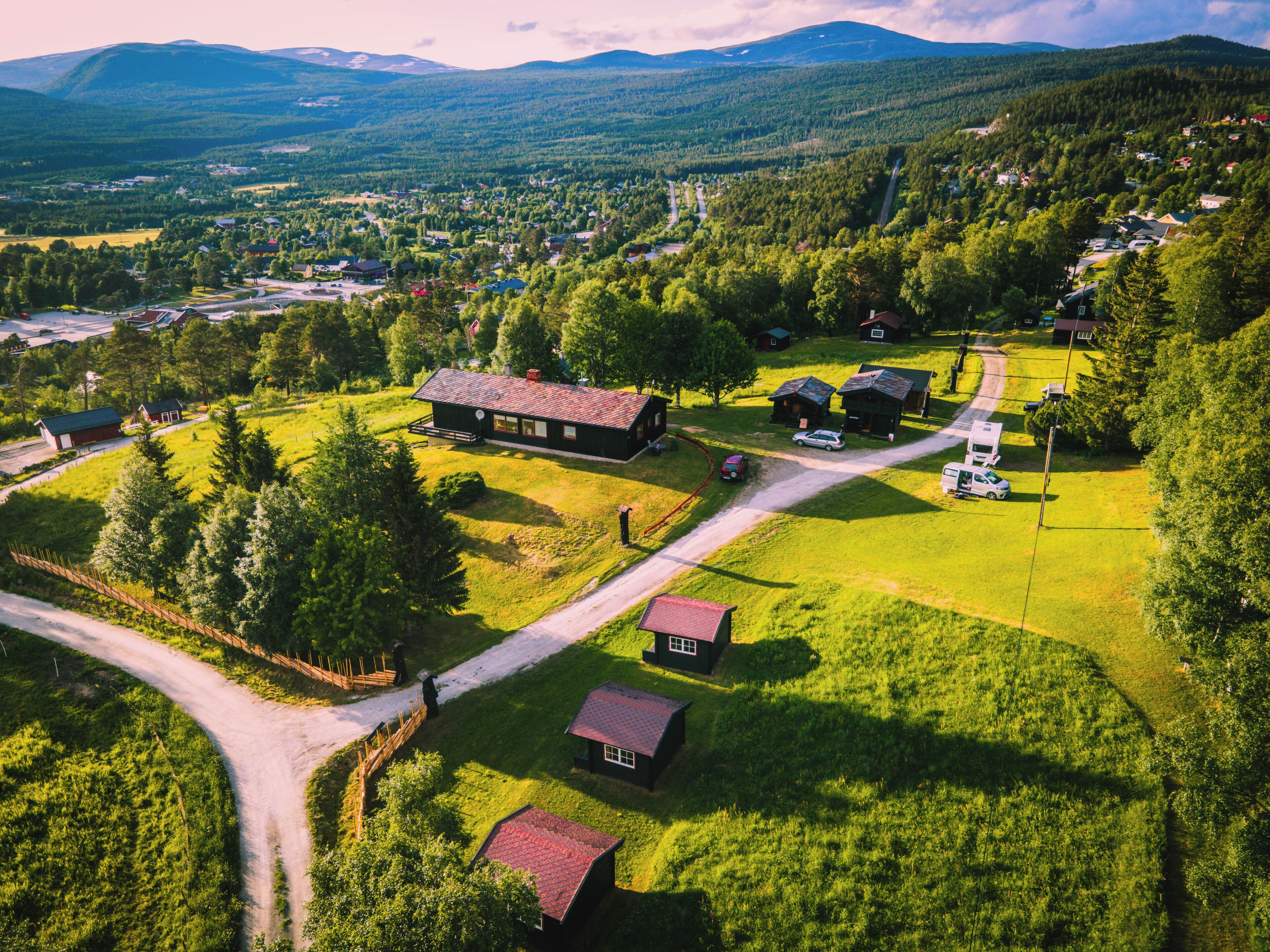 An aerial view of a rural area with a large house, smaller buildings, and a winding road.