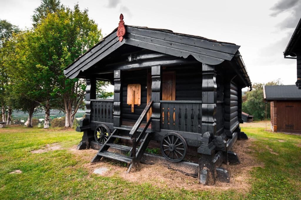 A rustic log cabin with a porch and wooden steps.