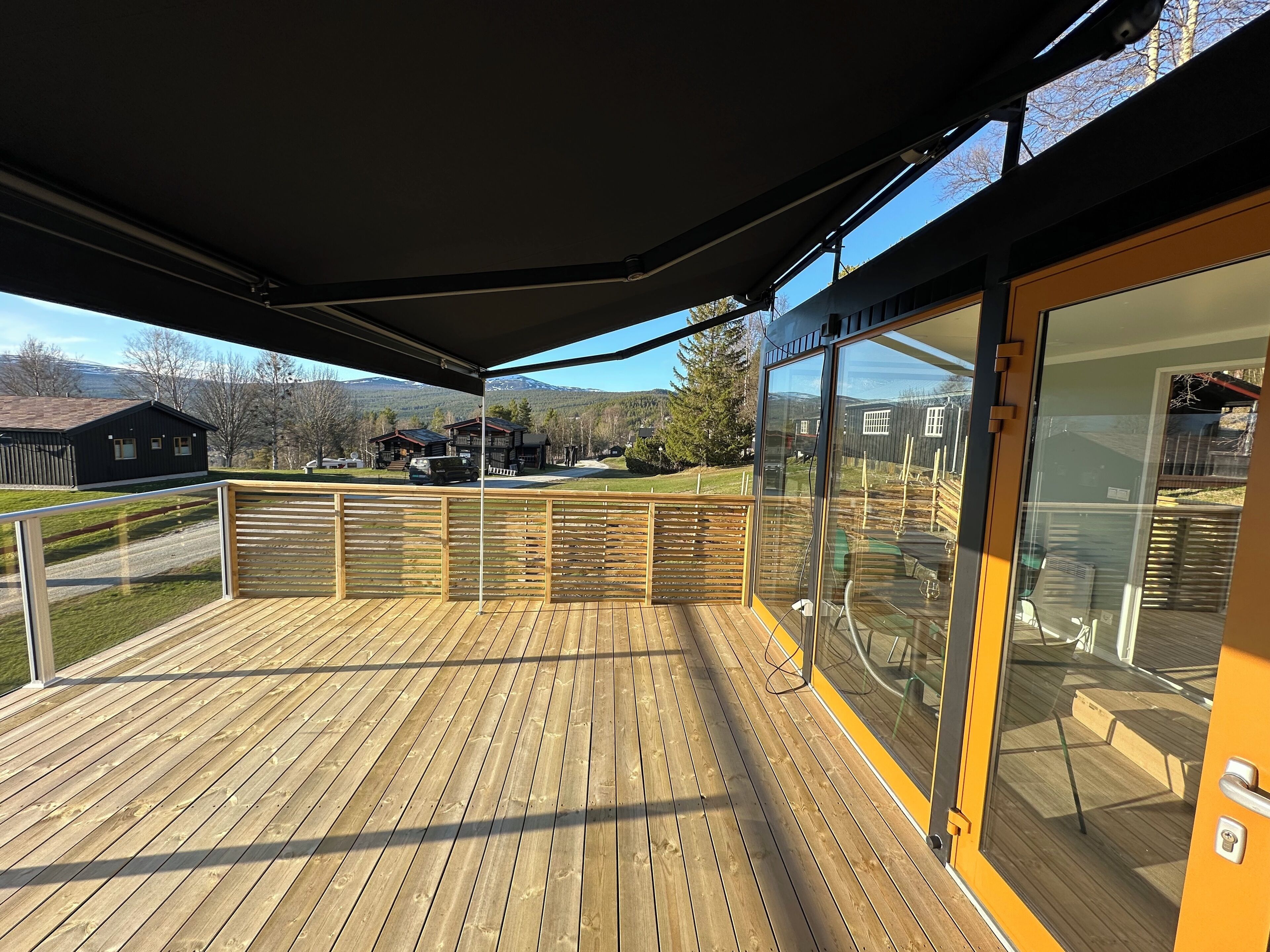 A wooden deck with a glass door leading to a patio area.