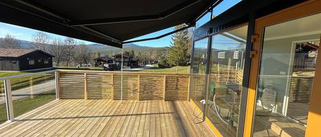 A wooden deck with a glass door leading to a patio area.