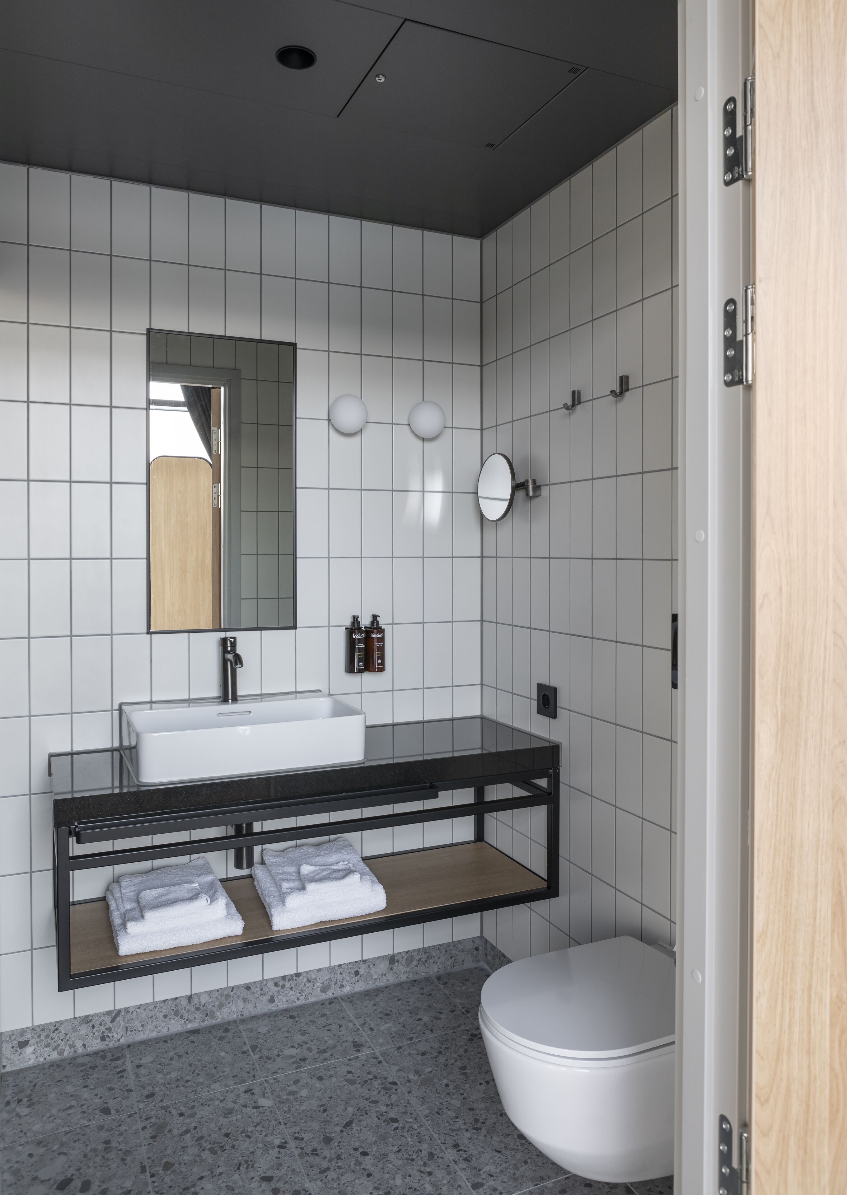 Un baño moderno con lavamanos, espejo y retrete blancos.