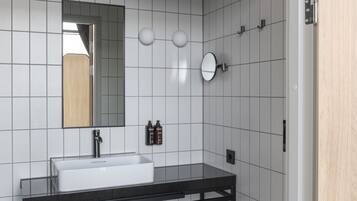 Un baño moderno con lavamanos, espejo y retrete blancos.