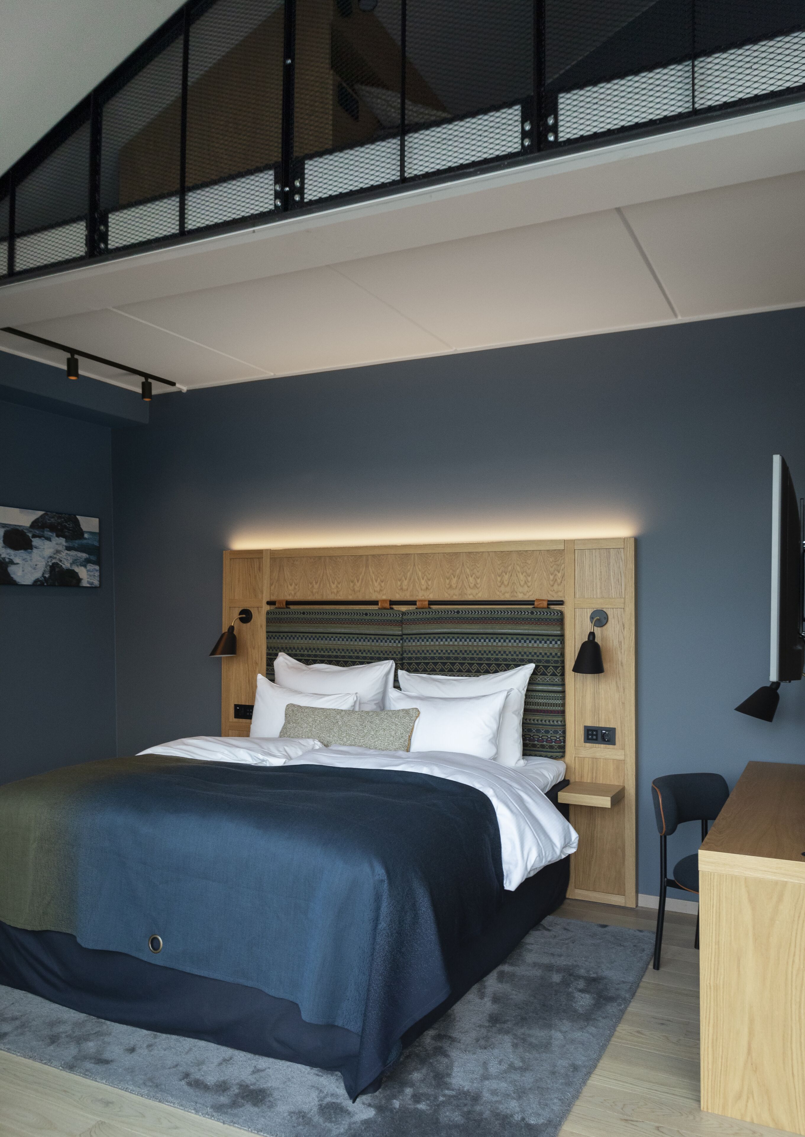 A modern bedroom with a bed, bedside tables, and a desk.