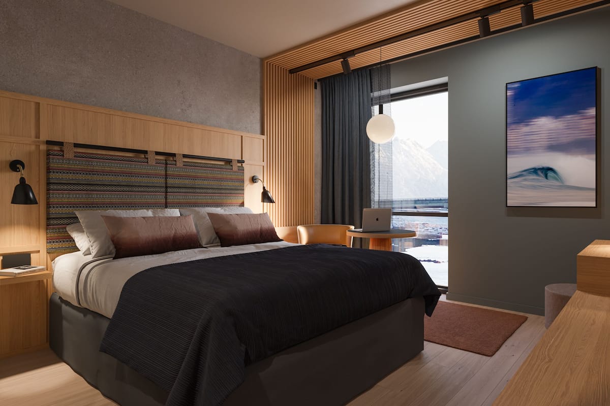 A modern bedroom with a bed, a desk, and a view of mountains.