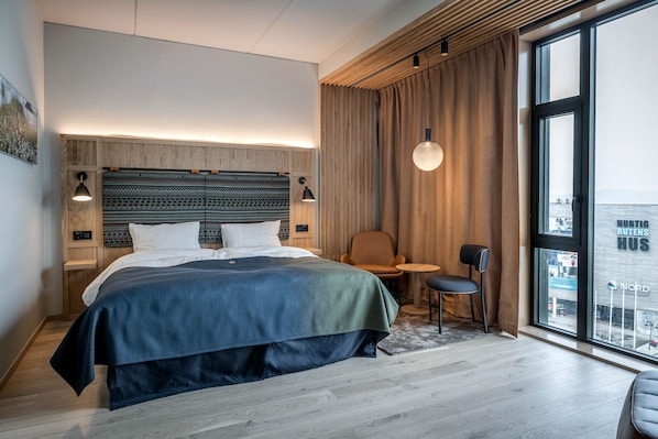 Habitación de hotel moderna con una cama grande, un escritorio y vistas a la ciudad.
