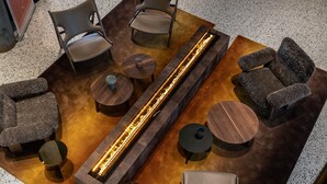 A modern lounge area with a long, illuminated water feature, multiple seating options including sofas and chairs, and small round tables. - Quality Hotel Richard With (Hadsel)