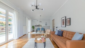 A modern living room with a sofa, coffee table, and dining area. - Homey 2BR Apartment in Cholargos (Papagou-Holargos)