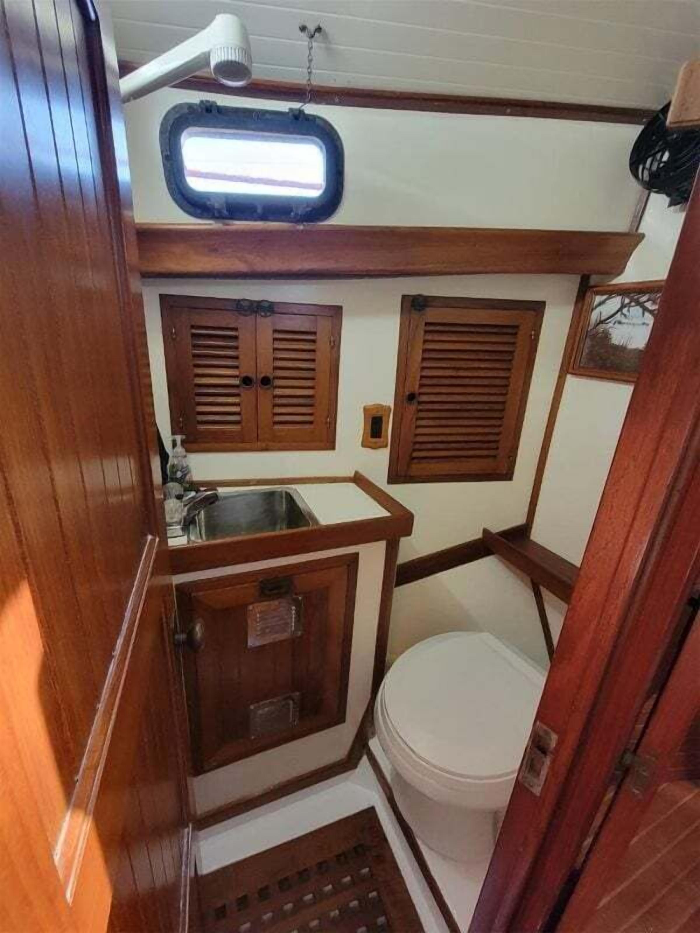 Een kleine badkamer met een wastafel, toilet en raam.