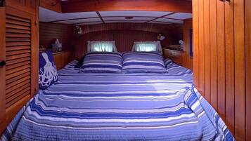 L’intérieur d’une cabane avec un lit, des murs en bois et une fenêtre avec des rideaux.