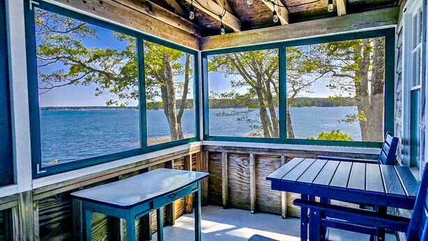 Een chalet met houten inrichting, grote ramen, een tafel en een bank.