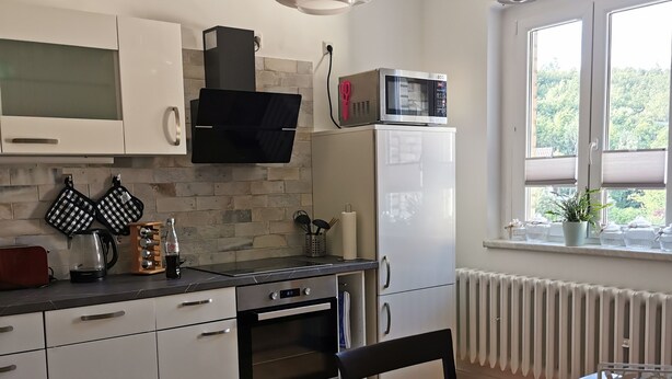 Eine moderne Küche mit weißen Schränken, einem eingebauten Backofen, einer Mikrowelle und einem Essbereich mit Tisch und Stühlen.