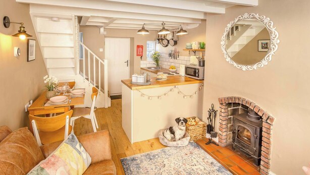 Een knusse woonkamer met een open haard, een eethoek en een keuken met een trap.